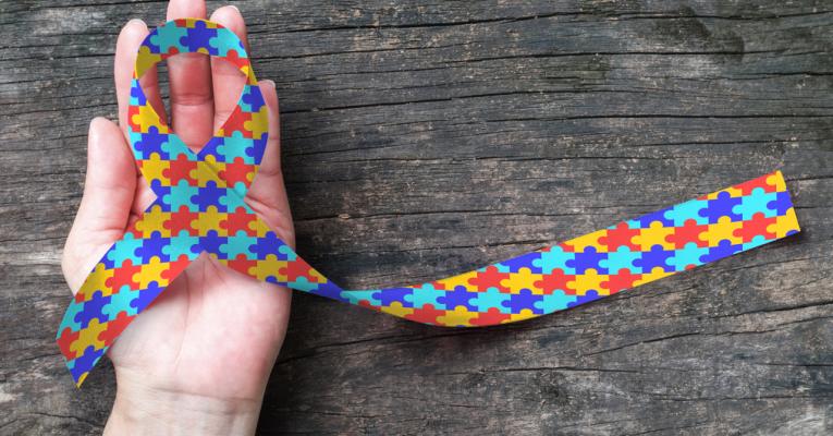 Hand holding puzzle piece Autism ribbon
