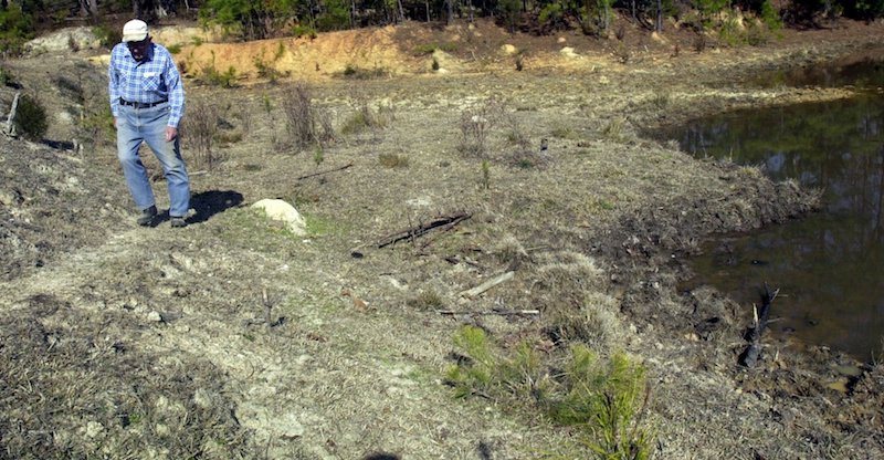 farmer examining dried up irrigation pond
